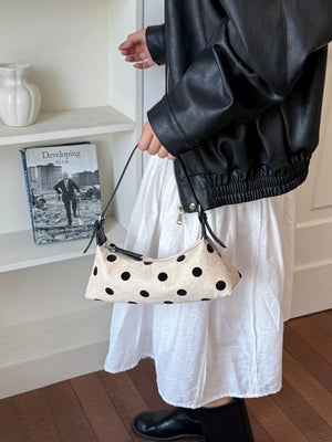black crossbody bag featuring adjustable strap and polka dot