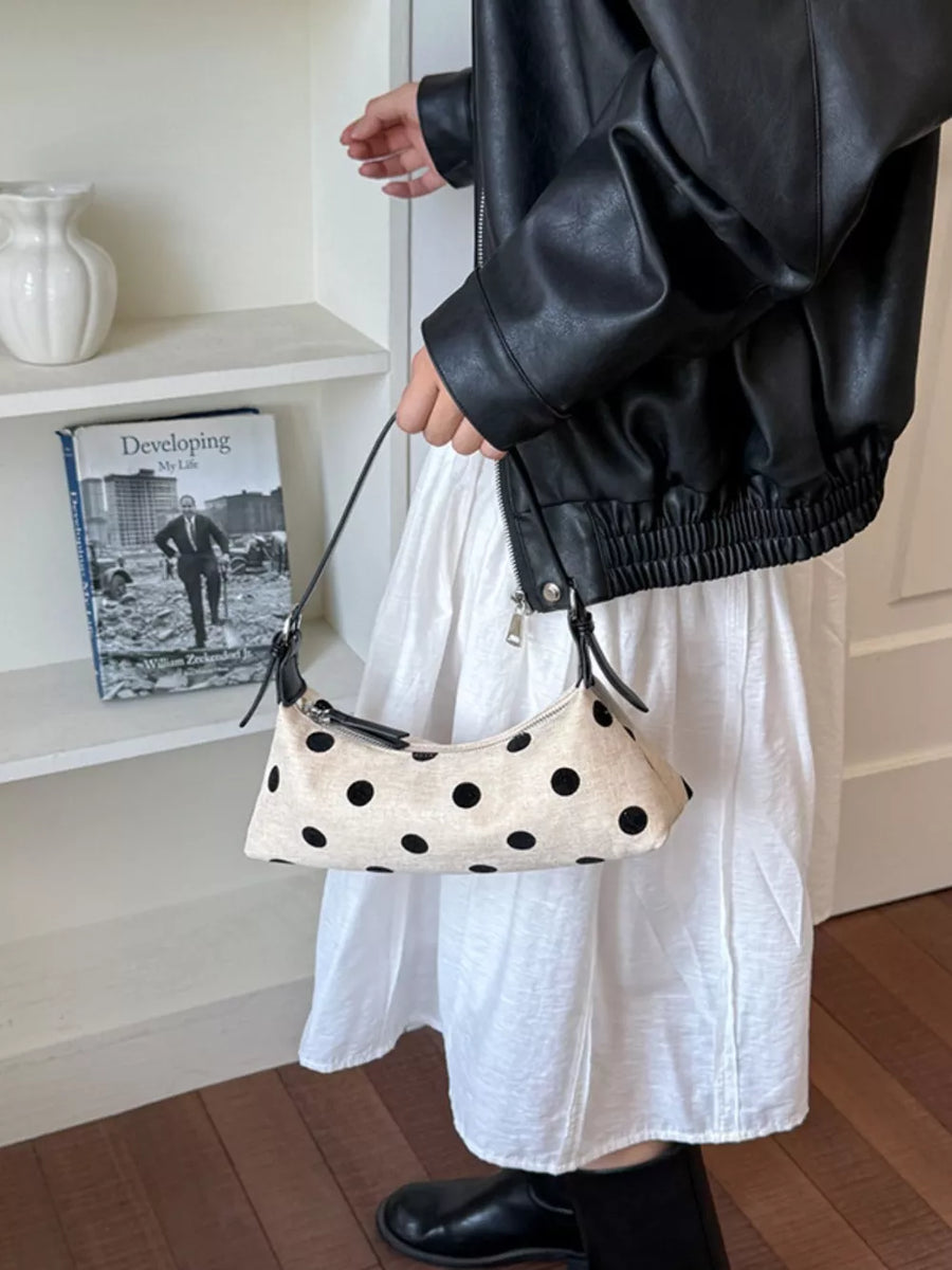 black crossbody bag featuring adjustable strap and polka dot