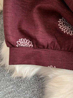 Burgundy maternity joggers with white paisley print and elastic cuffs.