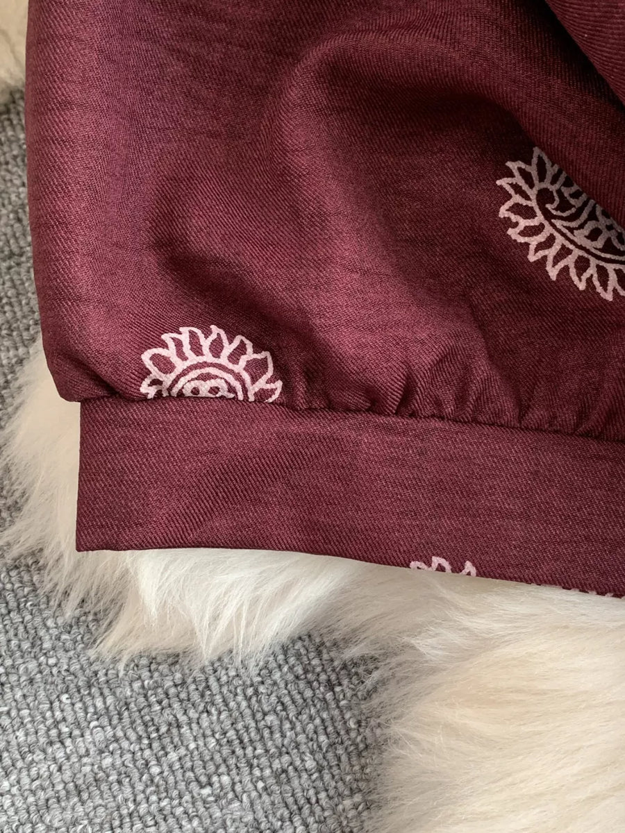 Burgundy maternity joggers with white paisley print and elastic cuffs.