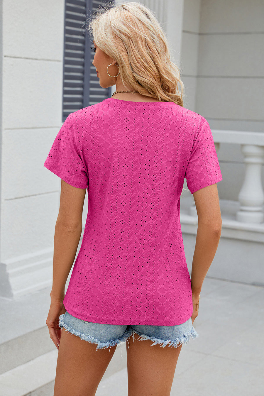 Eyelet wrap V-neck top in hot pink with short sleeves and a textured pattern.