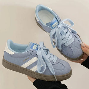 Pastel blue suede trainers with white signature stripes and lace-up closure.