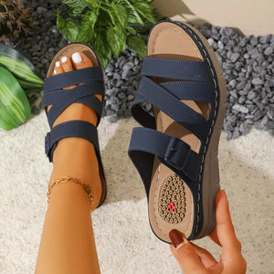 Blue multi-strap wedge sandals with adjustable buckle and criss-cross detail.