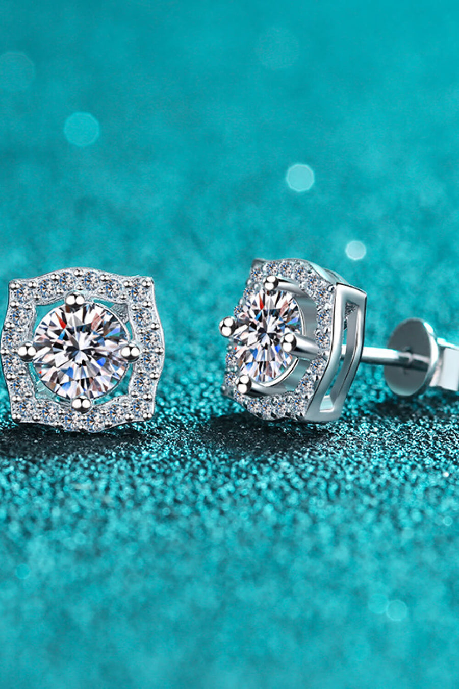 Scalloped halo moissanite stud earrings in silver with a central round cut stone surrounded by smaller stones.