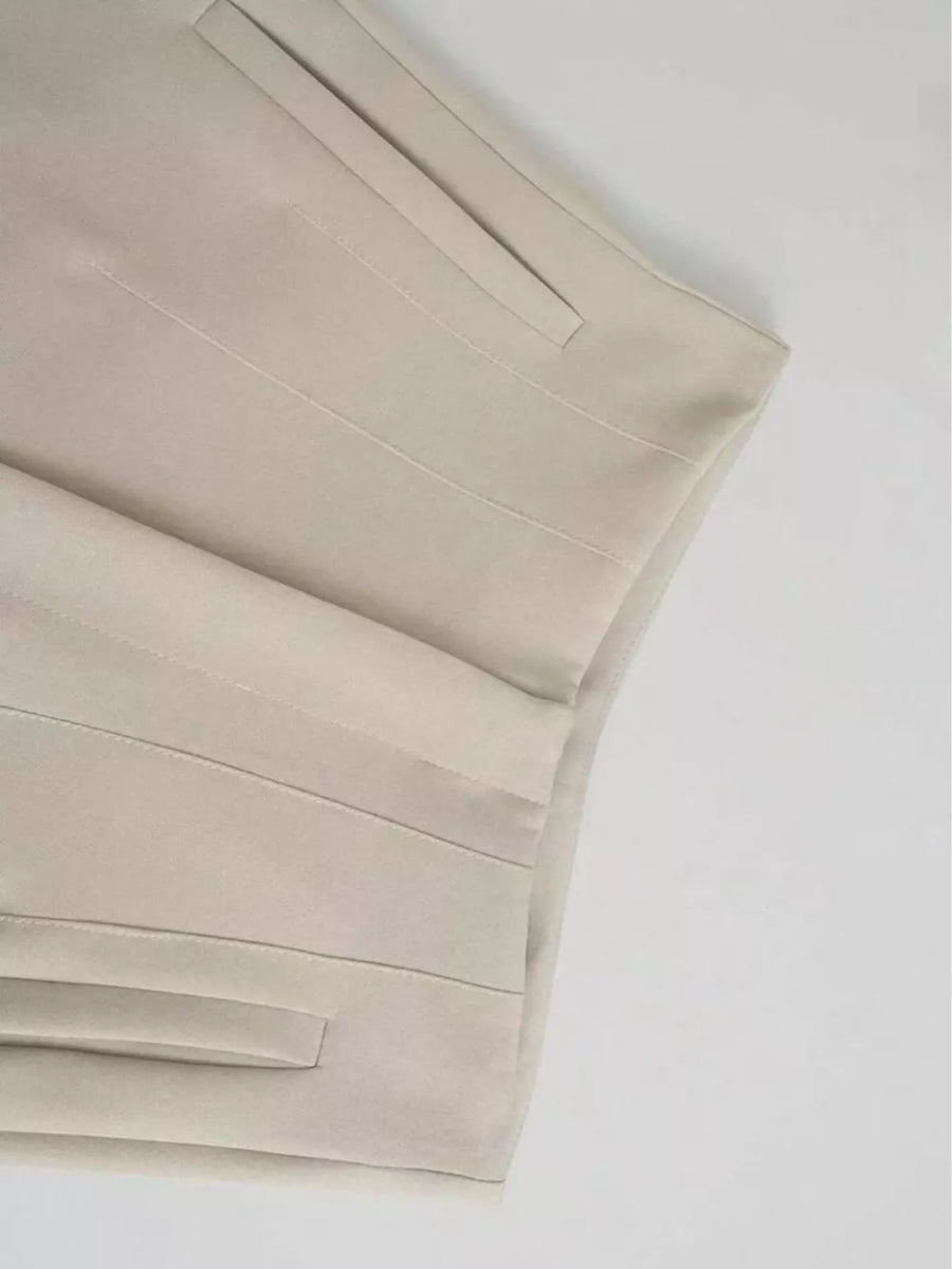 Beige high-waisted straight-leg pants with seam detail and pocket.