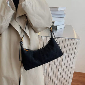 Chic suede crescent shoulder bag in black with gold hardware and adjustable strap.