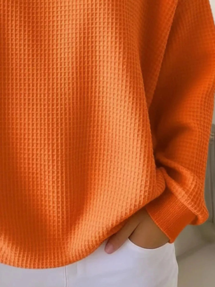 Orange waffle knit sweater with button detail and cuffed sleeves.