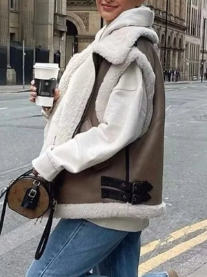 Brown faux shearling vest coat with buckle details, worn over a white hoodie.