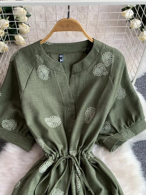 Green paisley print drawstring jumpsuit with button front and short sleeves.