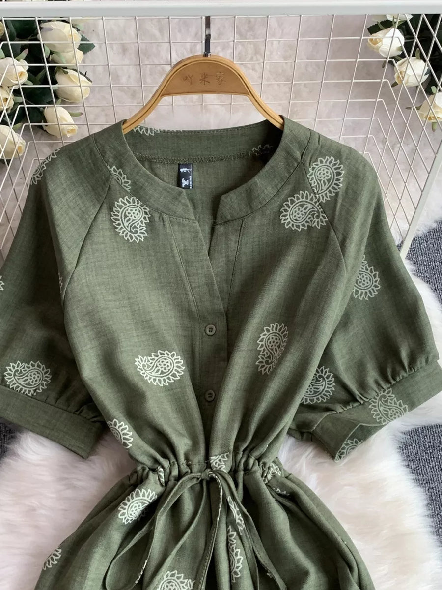 Green paisley print drawstring jumpsuit with button front and short sleeves.