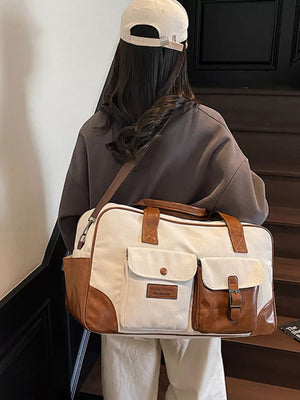 Sophisticated canvas travel bag in cream white with brown leather accents and multiple pockets.