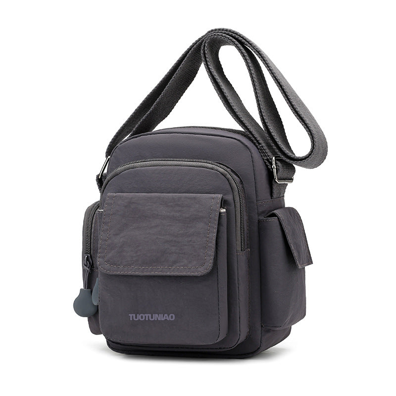 Gray lightweight nylon crossbody bag with multiple pockets and adjustable strap.