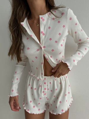 White ribbed knit pajama set with pink floral print and frill trim.