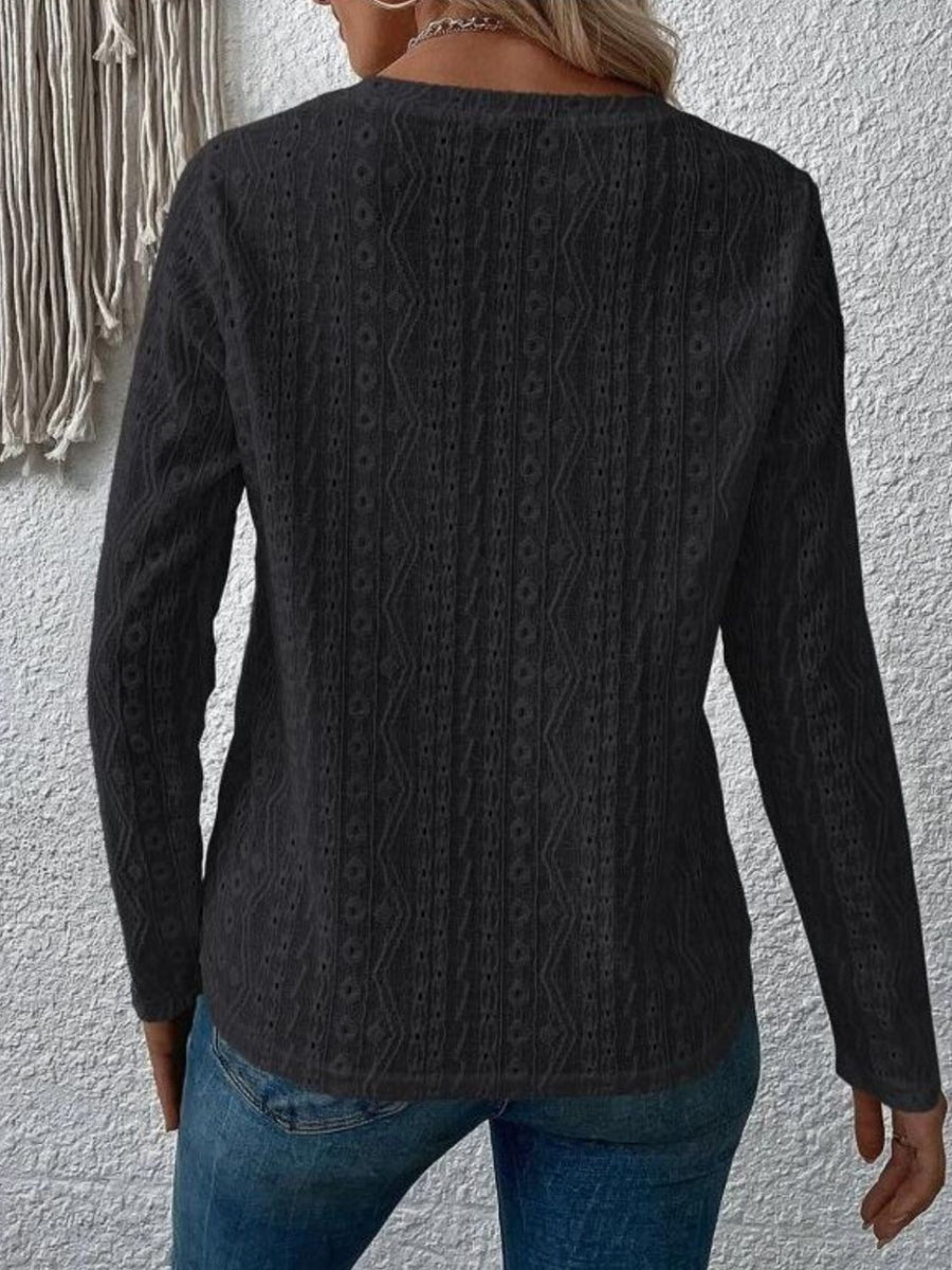 Black geometric eyelet long sleeve knit top with a textured pattern.