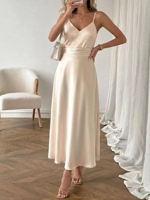 Lustrous V-neck maxi dress with spaghetti straps in a pale champagne color, featuring a cinched waist and A-line skirt.