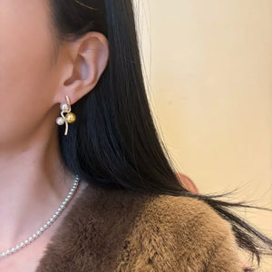 Gold and silver earrings with pearls and zircon accents, styled elegantly.