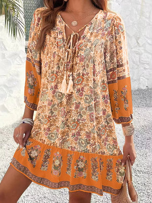 Vibrant floral tassel tie mini dress in ochre with peasant sleeves and tiered hem.