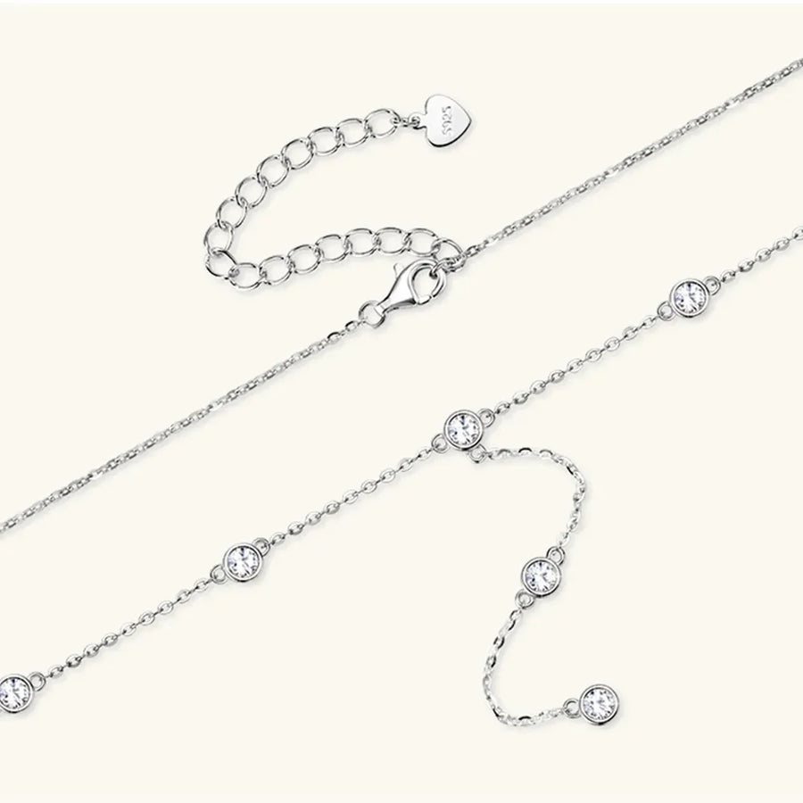 Silver lariat necklace with bezel-set moissanite stones and adjustable clasp.