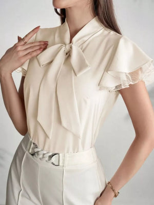 Beige tie-neck blouse with ruffle sleeves and lace trim.