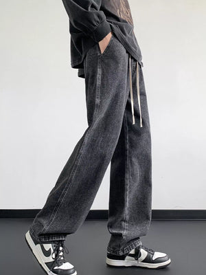 Oversized dark gray denim jeans with drawstring waist and loose fit.