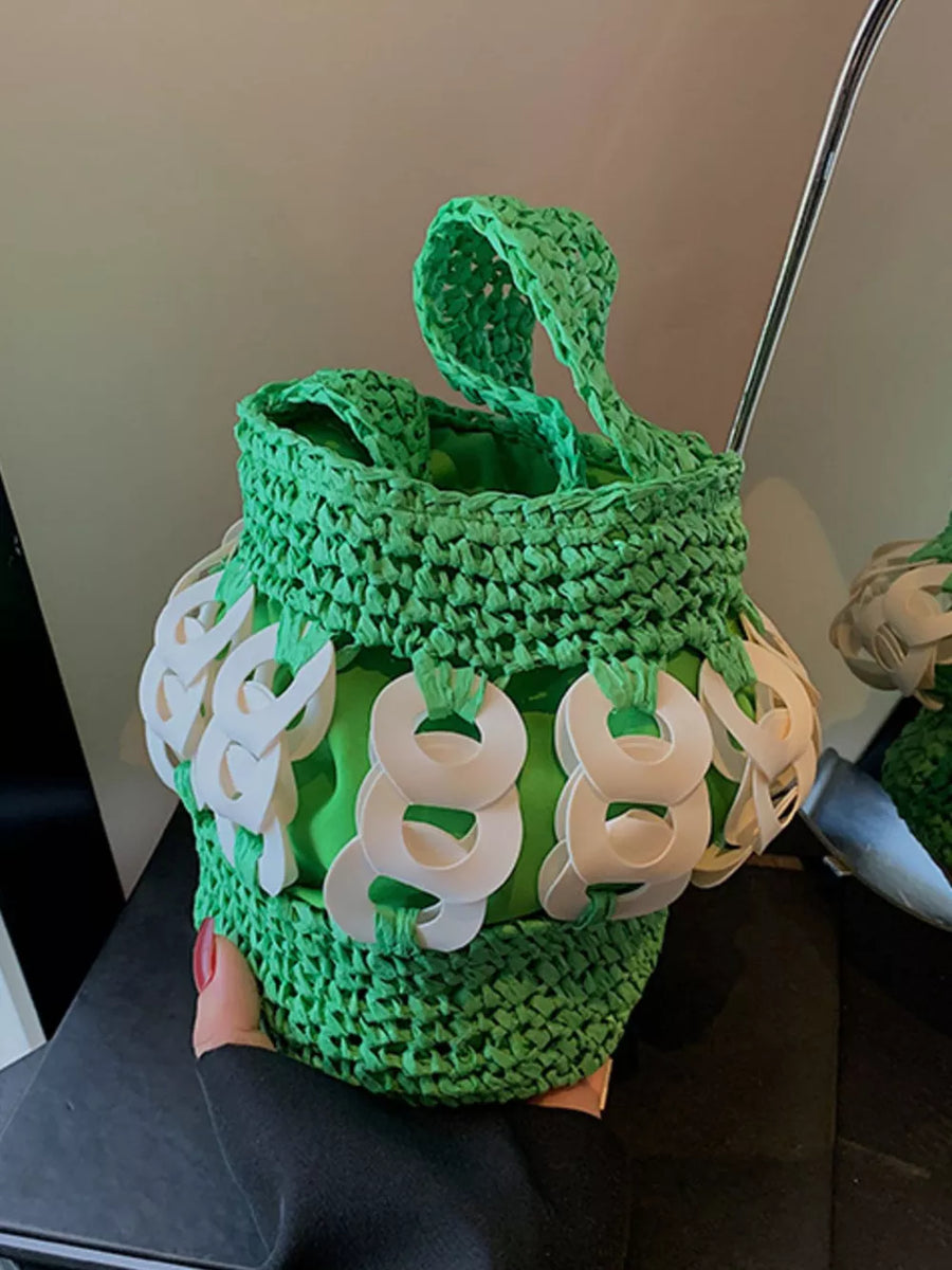 Green woven straw bucket tote with white ring embellishments and top handles.