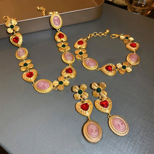 Gold cameo drop earrings with red heart and green flower accents.