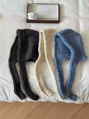 Cozy wool earflap beanie hat in black, off-white, and blue with long ear flaps.