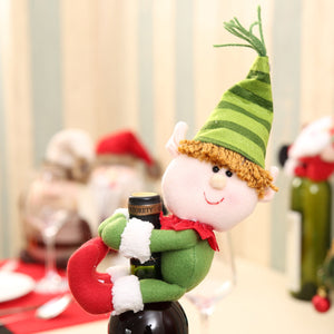 Plush elf bottle topper with green striped hat and red scarf, hugging a wine bottle.