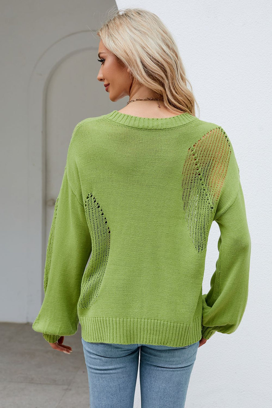 Green knit sweater with cutout details on the back and sleeves.