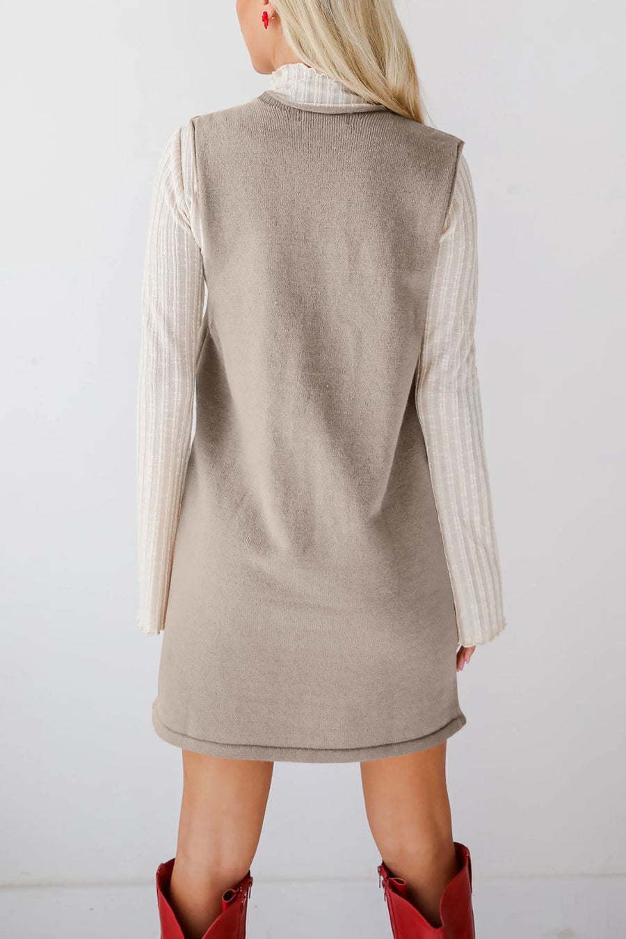 Sleeveless knit dress in camel with V-neck, layered over a striped long-sleeve top.