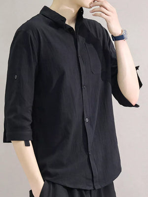 Black cotton button-down shirt with roll-up sleeves and chest pocket.