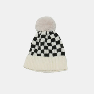 Checkerboard knit beanie with ivory ribbed cuff and faux fur pom.
