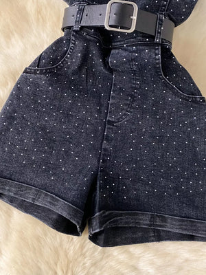 Black denim romper with rhinestone embellishments and a belted waist.