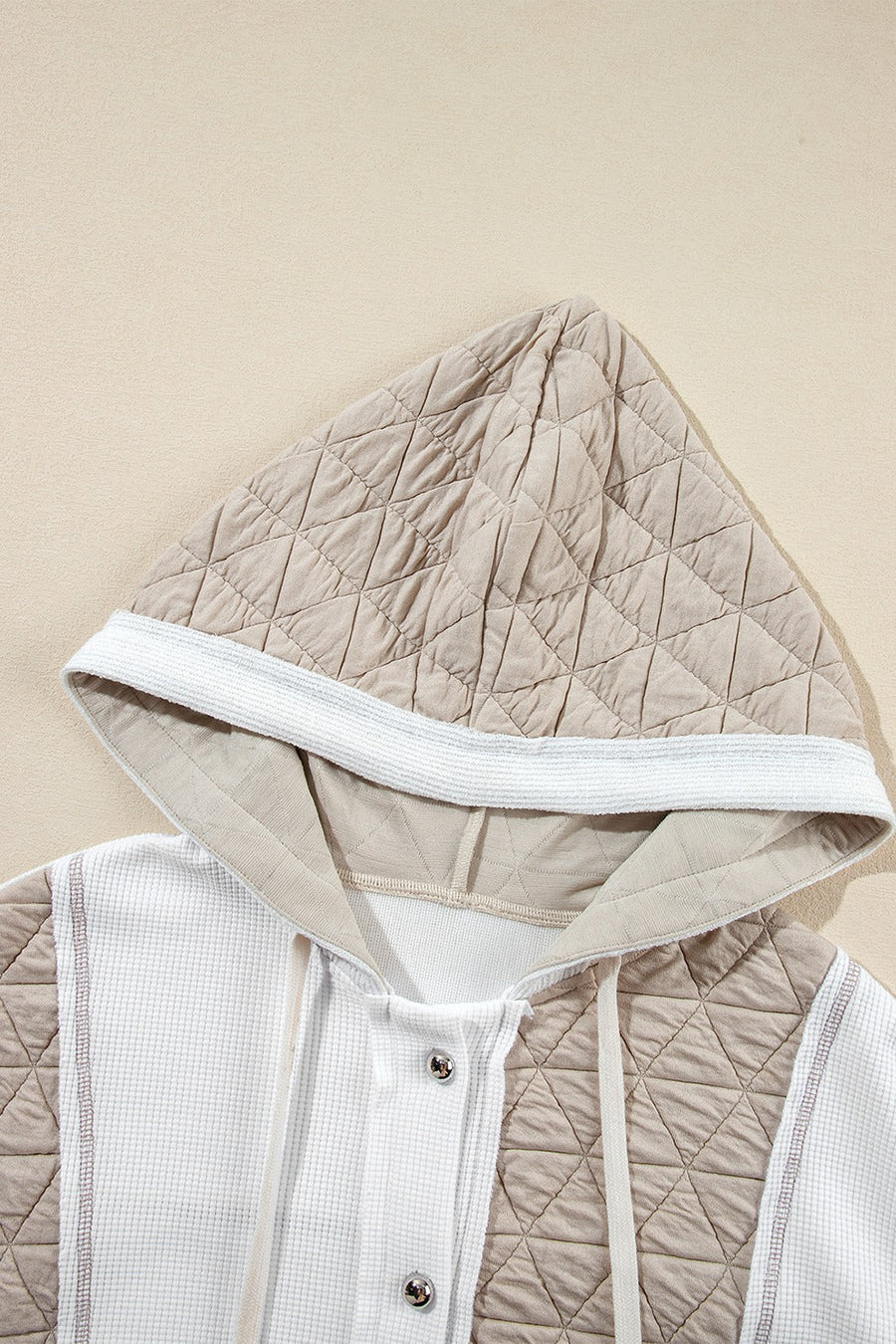 Hoodie with quilted panels and waffle knit fabric, featuring a drawstring hood and button closure.