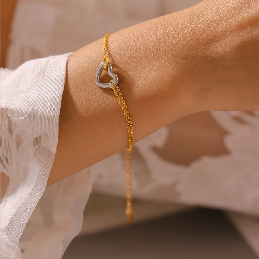 Two-tone heart charm bracelet with a delicate gold chain.