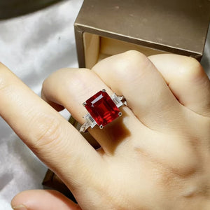 Sterling silver ring with large emerald-cut red moissanite and baguette side stones.
