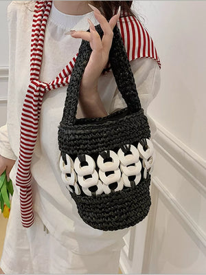 Black woven straw bucket tote with white ring detail and red striped scarf.