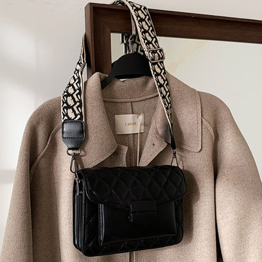 Black quilted flap crossbody bag with a patterned strap.