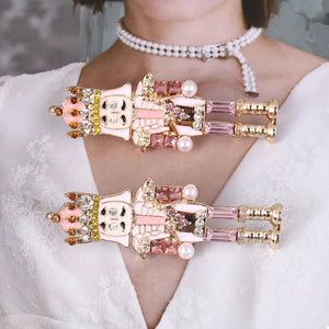 Blush pink nutcracker dangle earrings with gold accents and crystals.