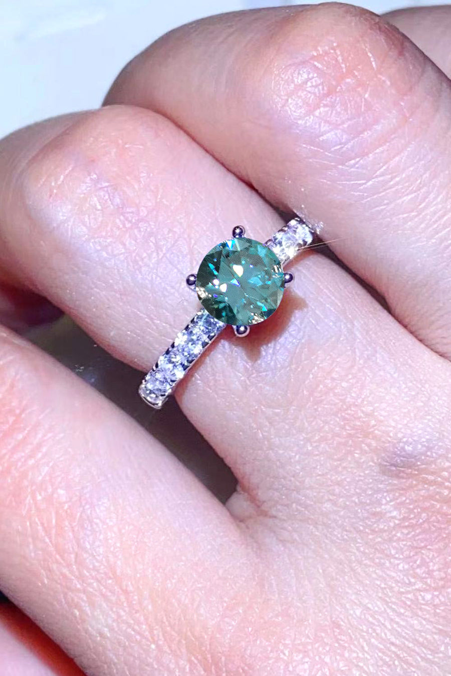 Celestial teal moissanite pavé ring with round center stone and diamond band.