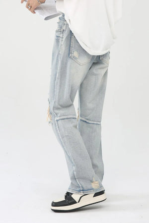 Light wash denim trousers with distressed knee slits and frayed hems.