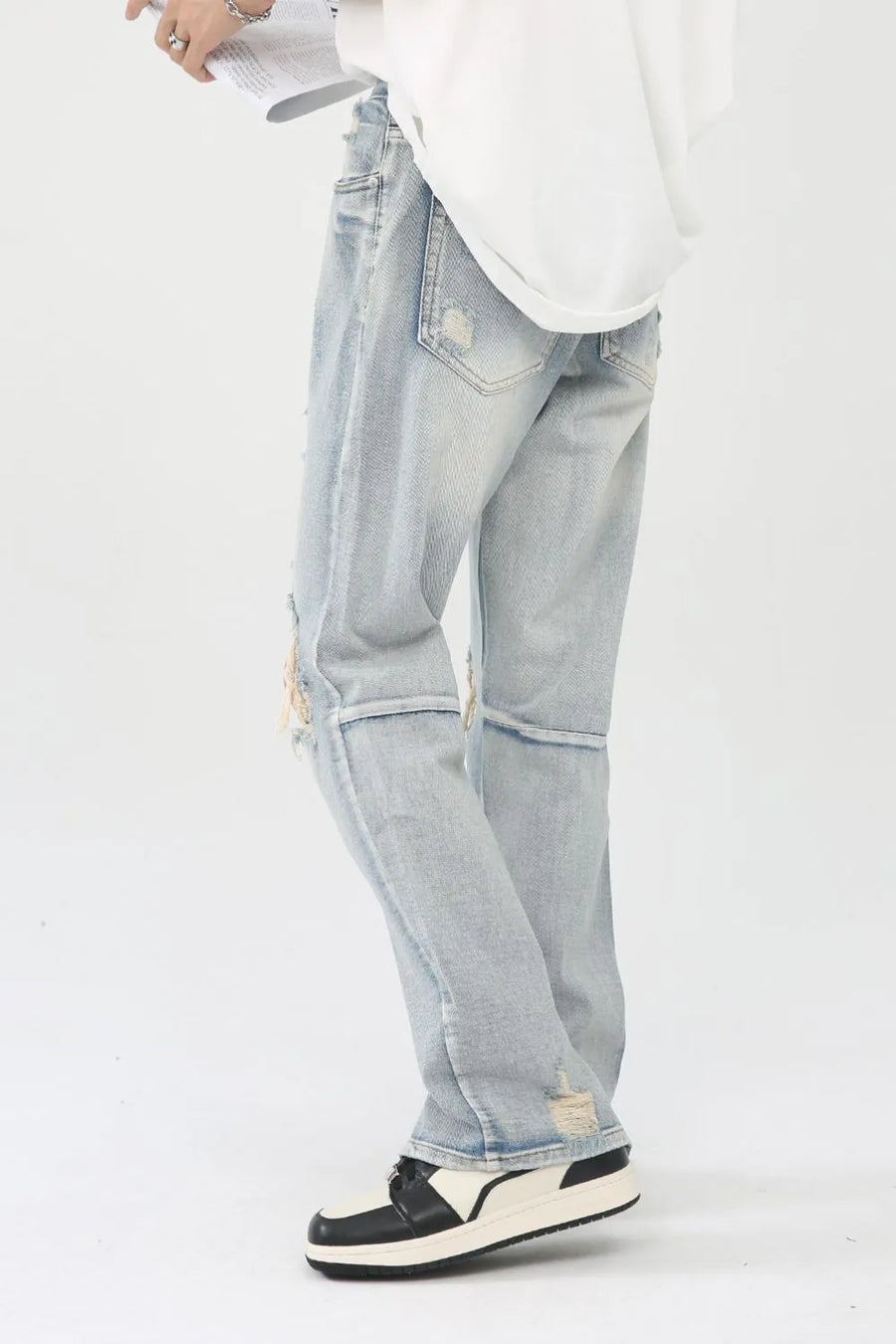 Light wash denim trousers with distressed knee slits and frayed hems.