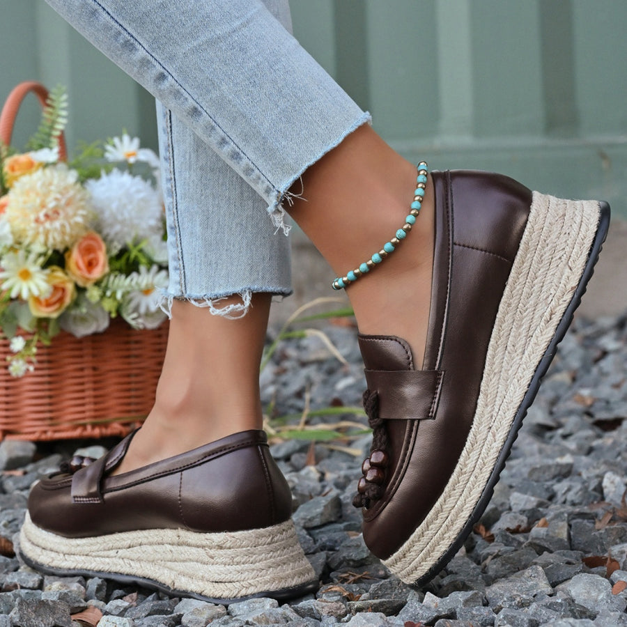 Brown espadrille wedge slip-on loafers with braided jute sole and tassel detail.