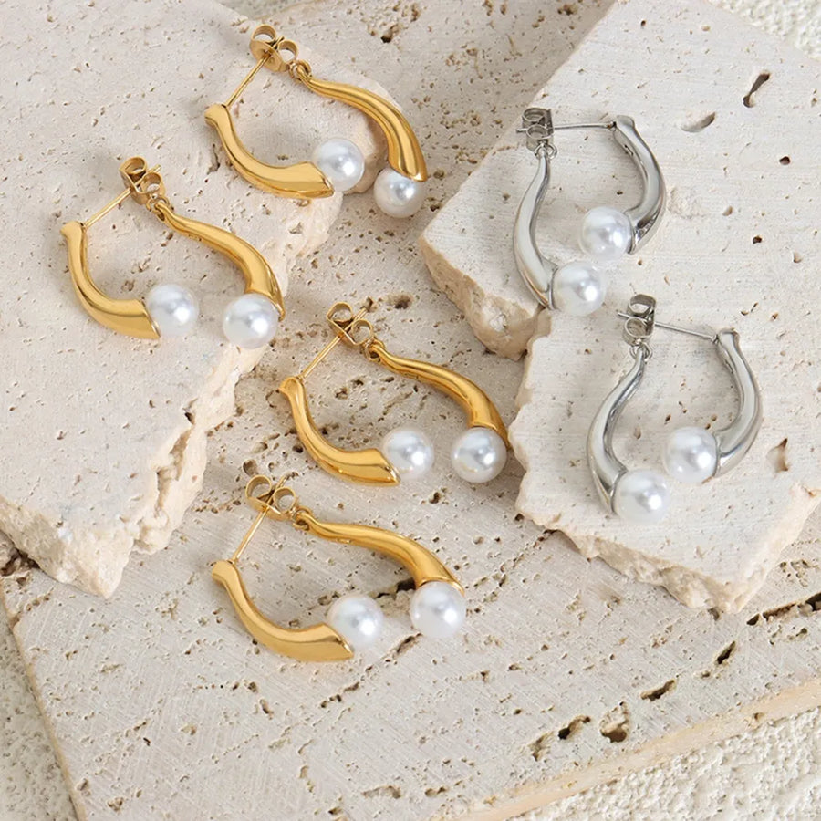 Gold and silver sculptural pearl drop hoop earrings with a modern design.