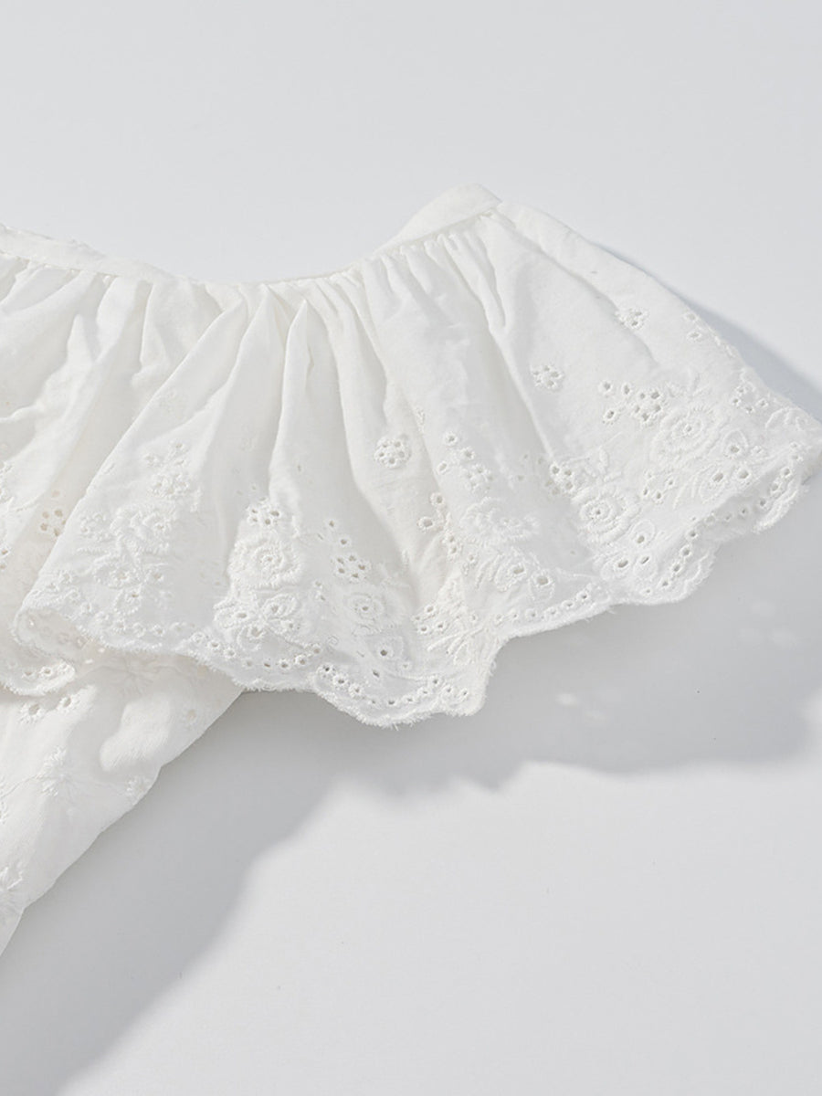 White eyelet tank top with ruffled trim and floral embroidery detail.