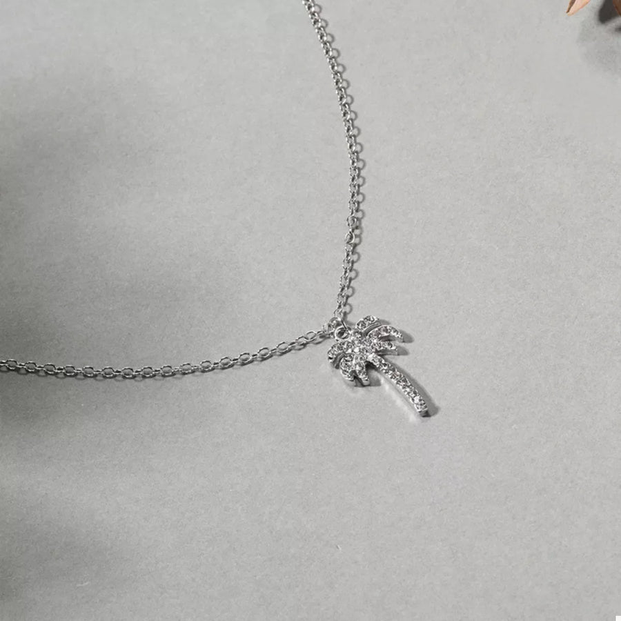 Silver palm tree pendant necklace with clear stones on a delicate chain.
