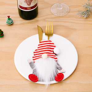 Festive gnome cutlery holder in red and white stripe with white beard and red feet on a plate.