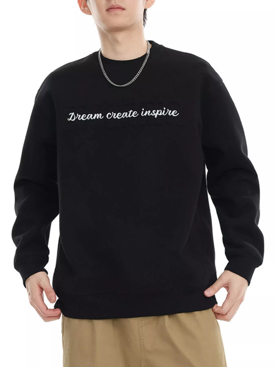 Black oversized crewneck sweatshirt with white embroidered text "Dream create inspire