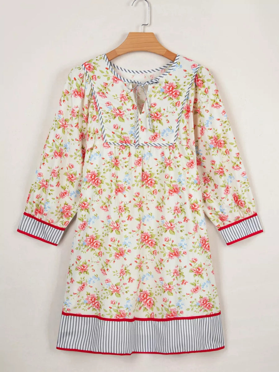 Floral cotton dress with puff sleeves, tie neck, and striped trim.