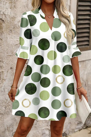 Women's white mini dress with playful green polka dots and flounce sleeves.